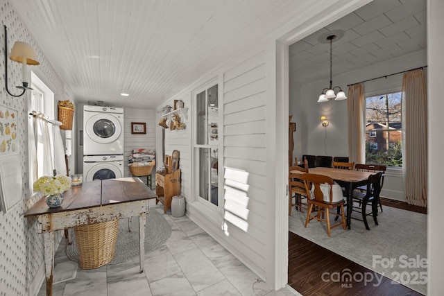 interior space with an inviting chandelier, stacked washer and dryer, and wooden ceiling