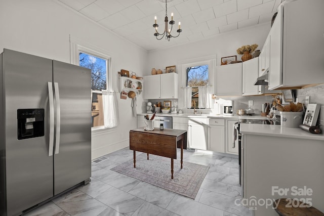 kitchen featuring white cabinetry, decorative light fixtures, appliances with stainless steel finishes, a notable chandelier, and decorative backsplash