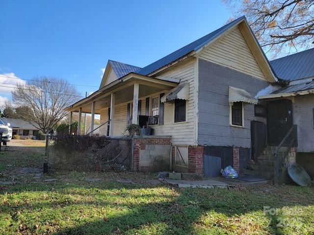 view of home's exterior with a lawn and covered porch