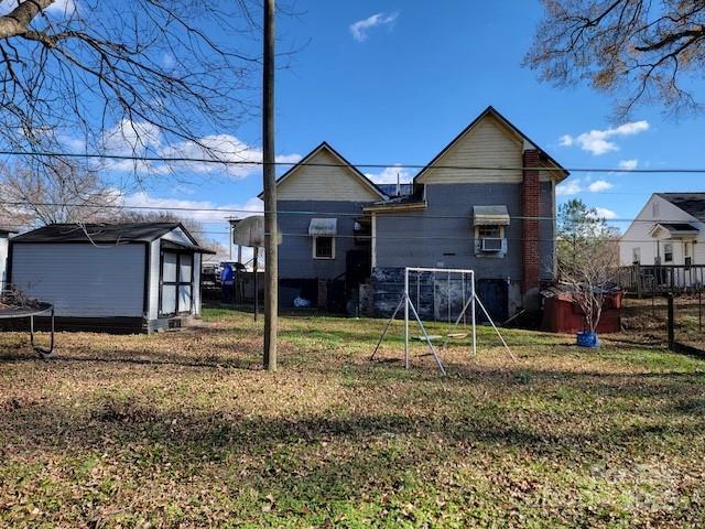 back of house with a trampoline and a lawn