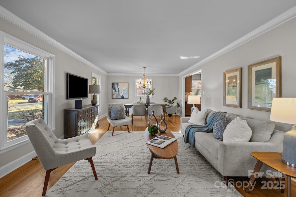 living room featuring ornamental molding, light hardwood / wood-style floors, and a notable chandelier