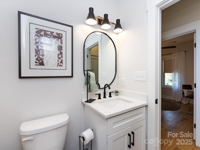 bathroom with wood-type flooring, vanity, and toilet