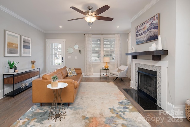 living room featuring a high end fireplace, dark wood-type flooring, ceiling fan, and ornamental molding