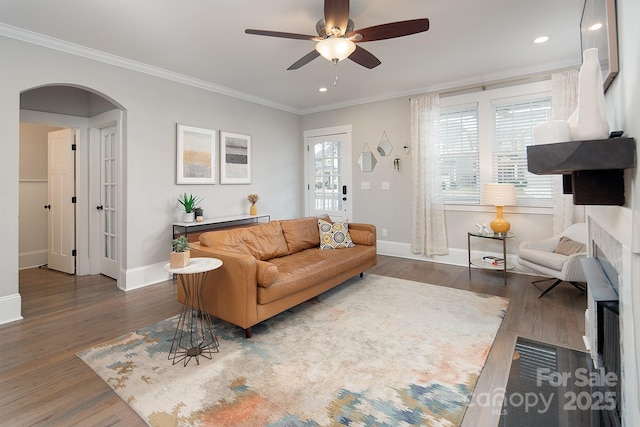 living room featuring ceiling fan, ornamental molding, and dark wood-type flooring