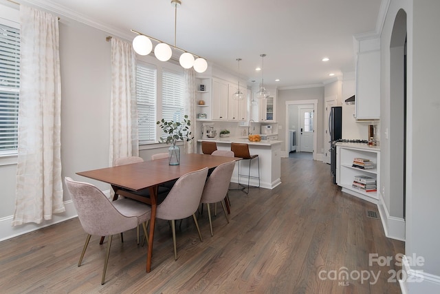 dining space featuring dark hardwood / wood-style floors, ornamental molding, and sink