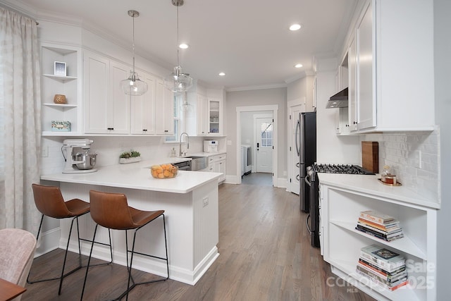 kitchen featuring gas range gas stove, crown molding, exhaust hood, decorative light fixtures, and white cabinets