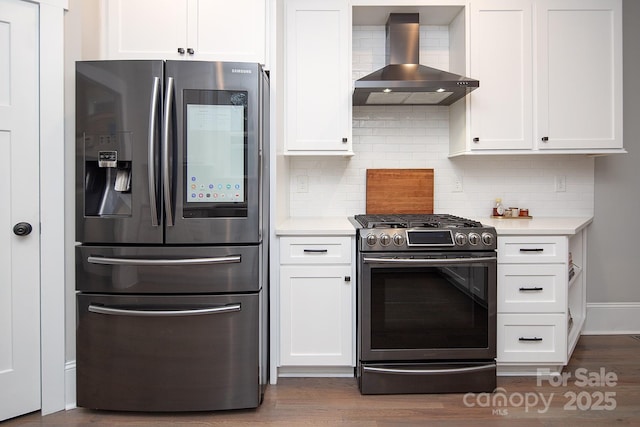 kitchen featuring stainless steel appliances, white cabinetry, and wall chimney range hood