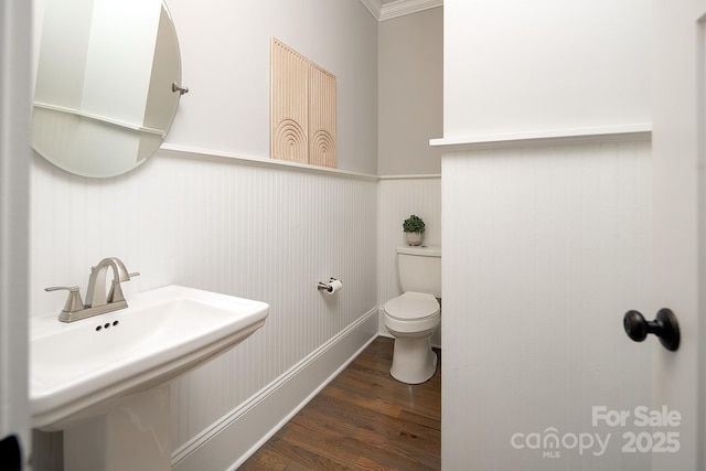 bathroom with hardwood / wood-style floors, toilet, crown molding, and sink