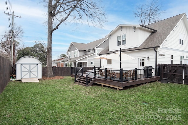 rear view of property featuring a yard, a storage unit, and a wooden deck