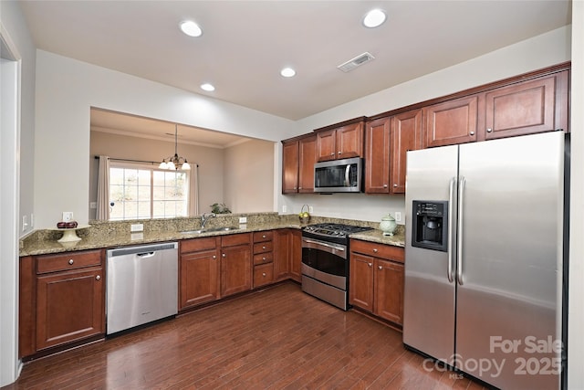 kitchen with hanging light fixtures, sink, appliances with stainless steel finishes, kitchen peninsula, and a chandelier