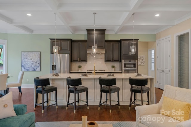 kitchen with a breakfast bar, stainless steel fridge with ice dispenser, a center island with sink, and pendant lighting