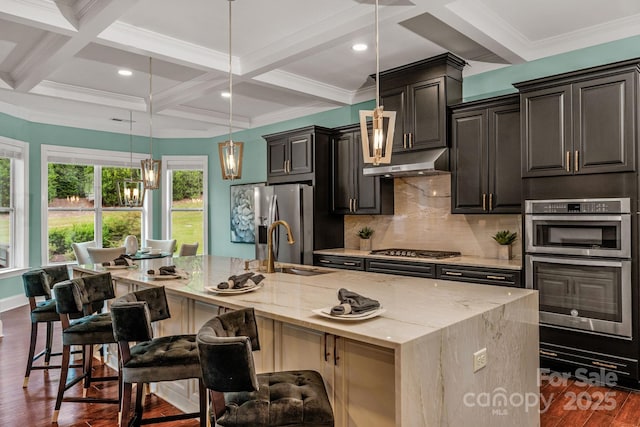 kitchen with a kitchen breakfast bar, a large island with sink, beam ceiling, and coffered ceiling