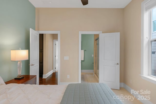 bedroom featuring ceiling fan, ensuite bath, and multiple windows