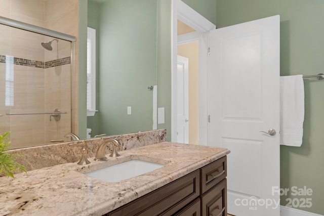 bathroom featuring vanity, a shower with shower door, and toilet