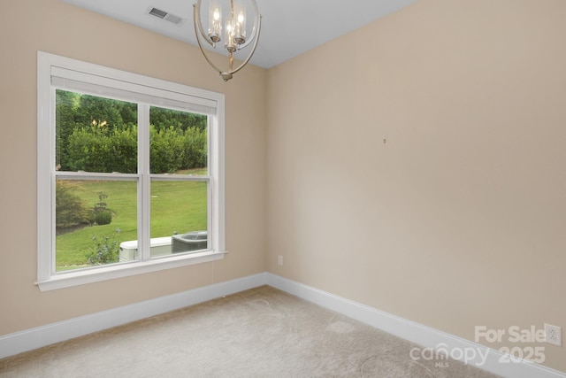 unfurnished room with a healthy amount of sunlight, carpet floors, and a chandelier