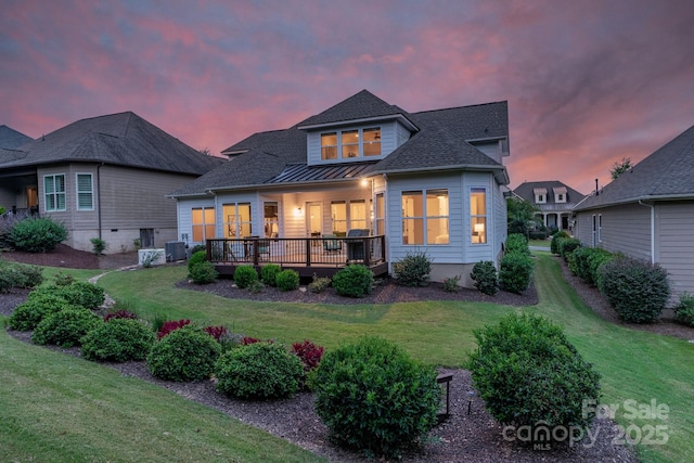 back house at dusk featuring a lawn and central AC