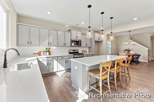 kitchen featuring sink, hanging light fixtures, stainless steel appliances, a breakfast bar, and a kitchen island