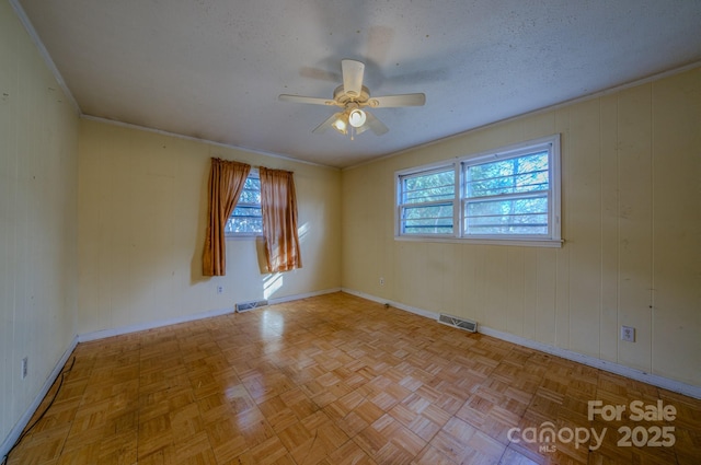 unfurnished room with a textured ceiling, light parquet floors, ceiling fan, and wood walls