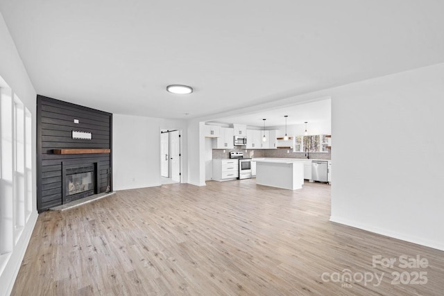 unfurnished living room with sink, light wood-type flooring, and a fireplace