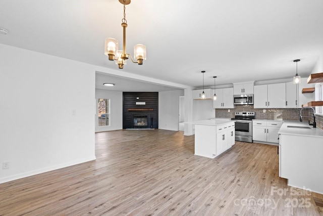 kitchen with sink, a kitchen island, pendant lighting, white cabinets, and appliances with stainless steel finishes