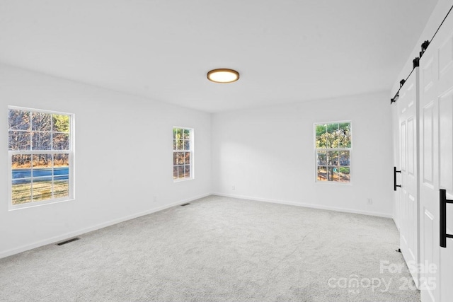 carpeted empty room featuring a barn door