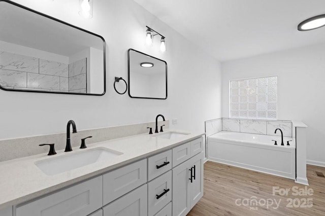 bathroom with a bathing tub, vanity, and hardwood / wood-style floors