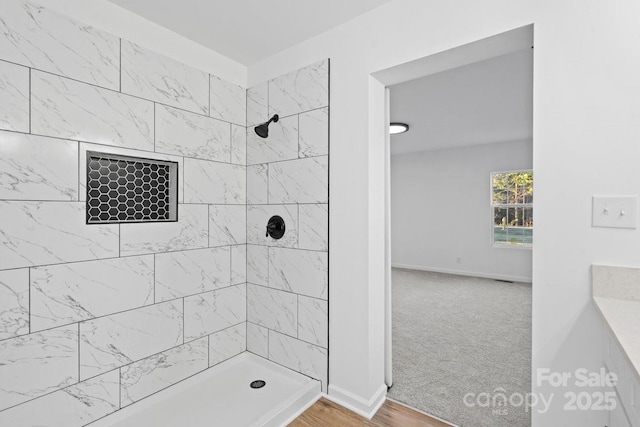 bathroom with tiled shower and hardwood / wood-style floors