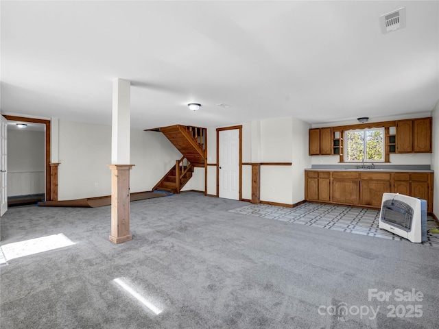 unfurnished living room featuring heating unit, sink, and light colored carpet