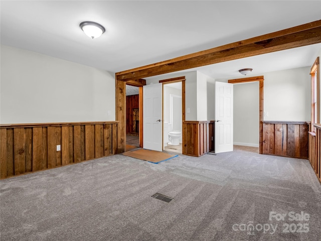 unfurnished room featuring wood walls and light colored carpet