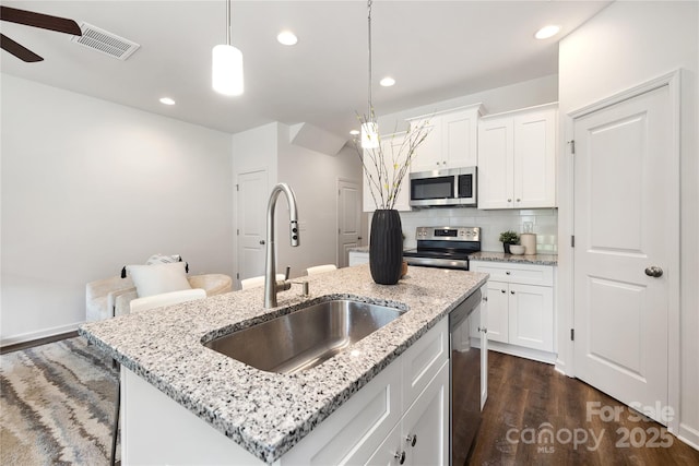 kitchen featuring sink, hanging light fixtures, stainless steel appliances, a kitchen island with sink, and white cabinets