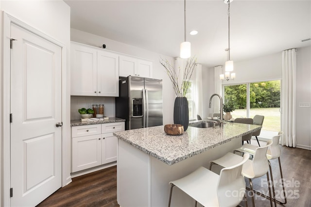 kitchen with backsplash, stainless steel fridge with ice dispenser, a center island with sink, and sink