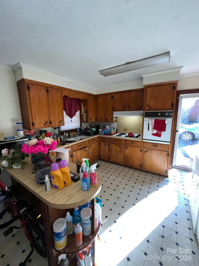 kitchen with a textured ceiling, crown molding, and white appliances