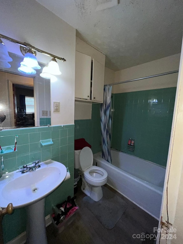 full bathroom featuring sink, tile walls, a textured ceiling, toilet, and shower / tub combo