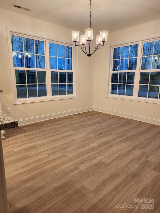 unfurnished dining area with hardwood / wood-style floors and an inviting chandelier