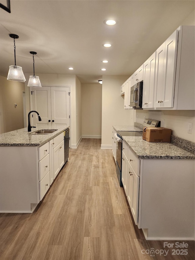 kitchen with decorative light fixtures, sink, white cabinets, and stainless steel appliances