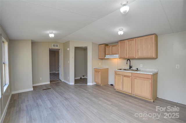 kitchen with lofted ceiling, light wood-type flooring, sink, and light brown cabinets