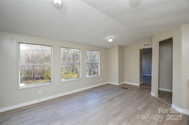 empty room with vaulted ceiling and hardwood / wood-style flooring