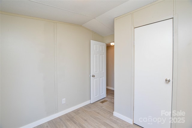 unfurnished bedroom featuring lofted ceiling and light hardwood / wood-style floors