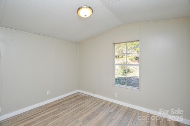 empty room with hardwood / wood-style floors and vaulted ceiling