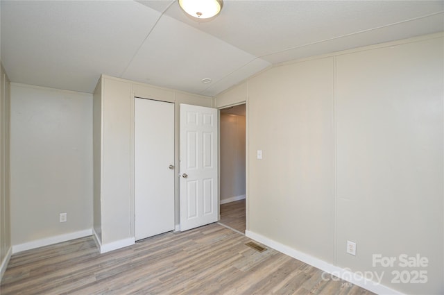 spare room featuring wood-type flooring and lofted ceiling