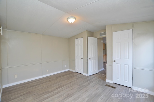 unfurnished bedroom with lofted ceiling and light hardwood / wood-style floors