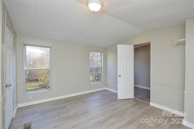 unfurnished bedroom with light hardwood / wood-style flooring and lofted ceiling