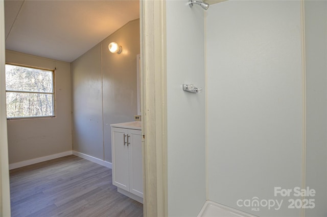 bathroom featuring wood-type flooring, vanity, and lofted ceiling