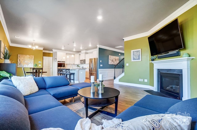 living room featuring crown molding, sink, a notable chandelier, and light wood-type flooring