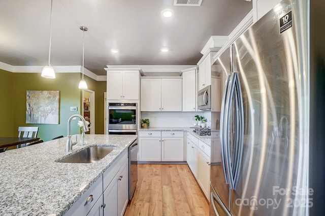 kitchen featuring pendant lighting, white cabinets, sink, appliances with stainless steel finishes, and light stone counters