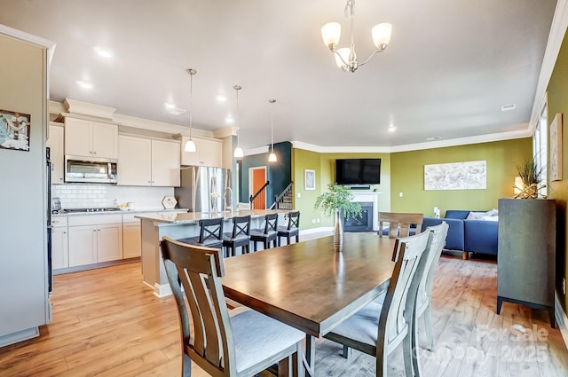 dining room featuring a chandelier, ornamental molding, and light hardwood / wood-style flooring