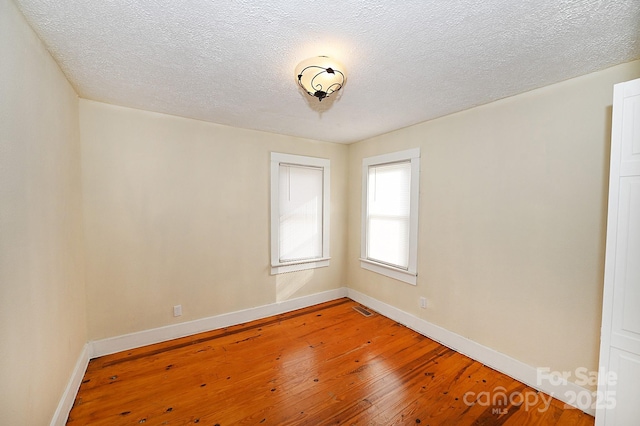 spare room featuring a textured ceiling and hardwood / wood-style flooring