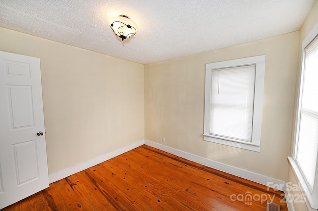 spare room with wood-type flooring, a textured ceiling, and a healthy amount of sunlight