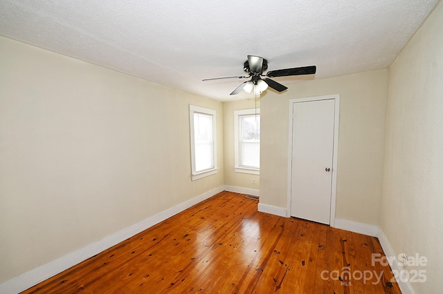 empty room featuring a textured ceiling, light wood-type flooring, and ceiling fan