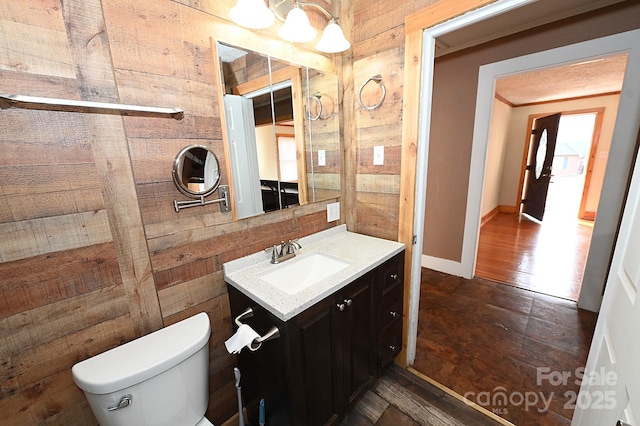 bathroom featuring vanity, toilet, and wooden walls